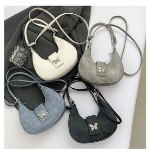 Détail de sacs bandoulière demi-lune avec boucle papillon en métal en quatre couleurs