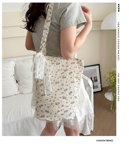 Detail of floral canvas tote bag featuring ruffled edges and delicate lace bow accent