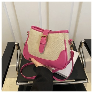 Close-up of a pink leather and beige woven canvas bucket bag held by a hand