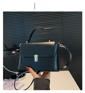 Close-up of black leather underarm bag with silver metallic lock and handle