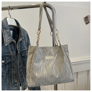 Dettaglio della trama plissettata argento e degli anelli dorati su questa borsa tote