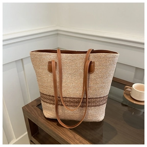 Detail of straw tote bag showing brown leather strap and neat stitching with inner lining