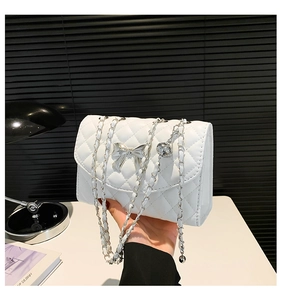 Détail du sac blanc matelassé avec une boucle argentée et un charmant pendentif en métal