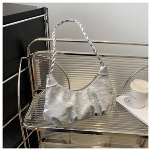 Gros plan sur le sac nuage argenté plissé avec bandoulière tissée sur étagère