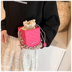 Detail of bright pink cube box bag with silver chunky chain and drawstring pouch