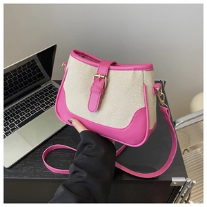 Detail of canvas bag with pink faux leather trim and golden metal buckles held by hand