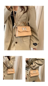 Detail of a beige crossbody bag featuring a silver metal bow buckle and slim shoulder strap