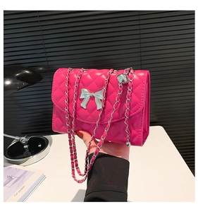 Détail du sac matelassé rose vif avec fermoir nœud argenté et bandoulière chaîne
