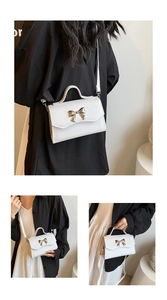 Detailed view of white crossbody bag with golden bow hardware and cross-grain leather texture