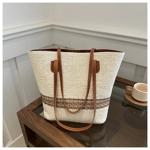 Close-up of woven straw bucket bag with brown lace trim and long leather handles