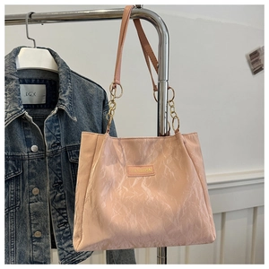Dettaglio della borsa tote rosa a pieghe con targa FASHION oro e tracolla a catena