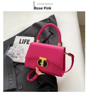 Detail of rose pink crocodile pattern handbag with woven handle and gold T-lock