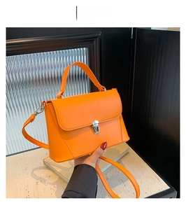Detail of orange PU leather handbag with silver metal buckle and top handle strap