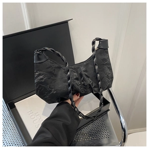 Détail du sac croissant plissé noir avec tissu texturé et poignée tressée