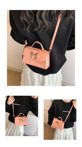 Detail view of pink PU crossbody bag with golden metal bow and top handle