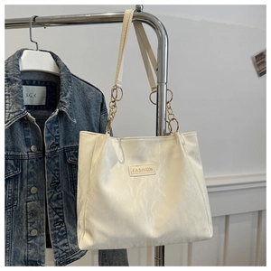 Dettaglio borsa tote bianca goffrata con catena dorata ed etichetta moda esclusiva
