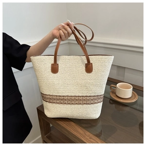 Close-up of summer straw tote bag with brown lace trim and faux leather handles