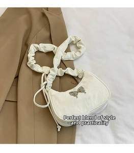 Detailed view of cream half-moon bag featuring silver butterfly buckle and pleated strap