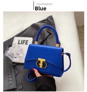 Close-up of royal blue crocodile pattern bag with woven handle and gold T-lock detail