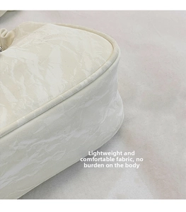 Detail view of the ivory underarm bag featuring a smooth marble pattern and premium fabric