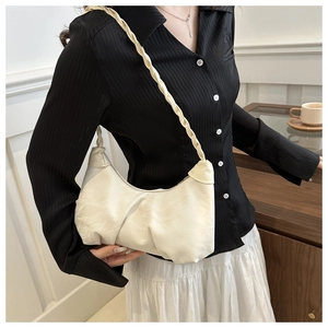 Détail du sac baguette plissé crème avec bandoulière tressée sur le mannequin