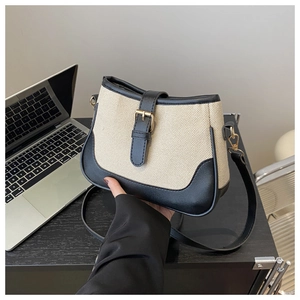 Close-up of a saddle-shaped canvas and leather crossbody bag with gold buckle detail