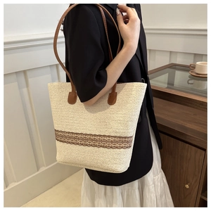 Detail of a straw tote bag with brown lace trim and leather straps for summer beach travel