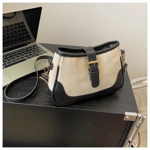 Detail of canvas and black leather crossbody bag on desk with laptop background