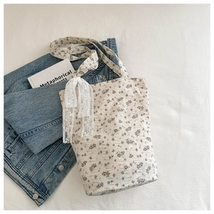Detail of floral tote bag with pleated texture and white lace bow decoration