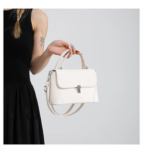 Detail of white structured handbag with silver metallic buckle on a black dress background