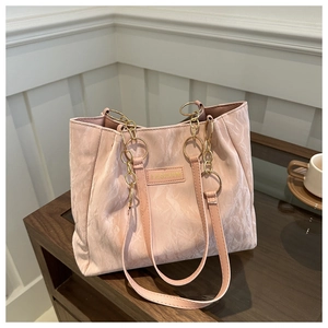 Dettaglio borsa tote rosa a pieghe con catena dorata ed etichetta moda su tavolo in legno