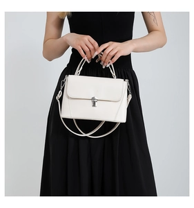 Close-up of white crossbody bag with silver push-lock buckle on high-quality synthetic leather