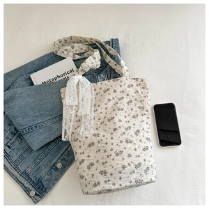 Detailed close-up of a floral tote bag with lace ribbon and textured cotton fabric