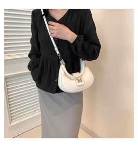Détail du sac demi-lune blanc avec boucle papillon argentée porté par un modèle
