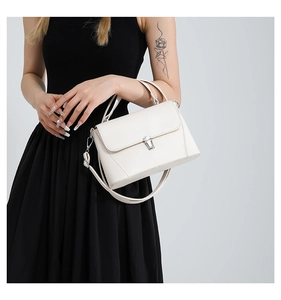 Detail of white leather crossbody bag with silver buckle and adjustable shoulder strap