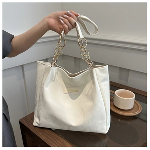 Dettaglio della borsa tote bianca in pelle con catena dorata e targhetta FASHION