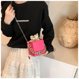 Close-up of pink bucket bag with embossed logo texture and silver chain strap