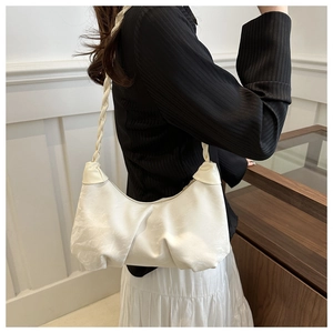 Détail du sac à bandoulière blanc plissé avec une sangle tressée sur un modèle féminin
