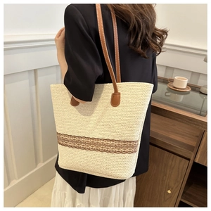 Beige woven tote bag with brown embroidery detail and leather straps on model shoulder