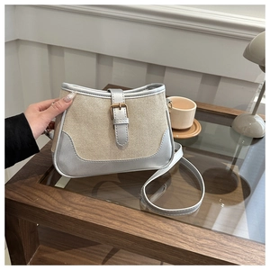 Detail view of stylish beige canvas and silver metallic leather handbag with buckle strap
