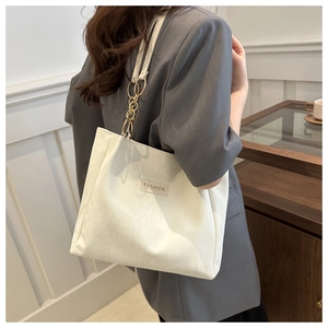 Dettaglio della borsa tote in pelle bianca con tracolla a catena dorata e logo Fashion