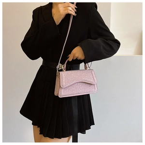 Pink sequin crossbody bag with gold hardware worn against a black dress for style