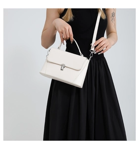 Detail of off-white faux leather handbag with silver metal lock and top handle