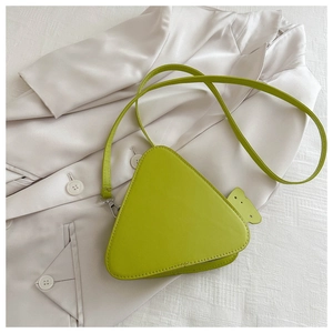 Dettaglio della borsa a tracolla a triangolo verde lime con ciondolo su tessuto blazer