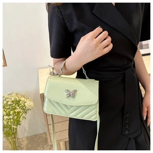 Detail of mint green crossbody bag with silver butterfly and V-shaped quilting