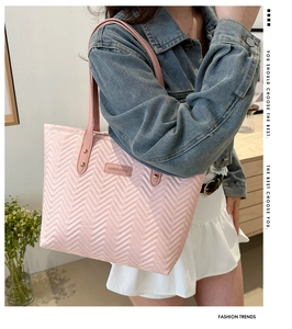 Detail of pink quilted tote bag with V-shaped stitching and golden metal rivets