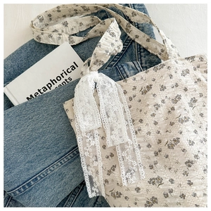 Detail of floral tote bag featuring white lace bow and textured puckered fabric