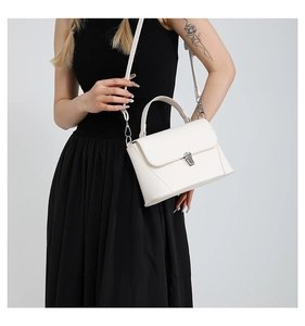 Detailed view of a white minimalist leather small square bag with silver metal clasp