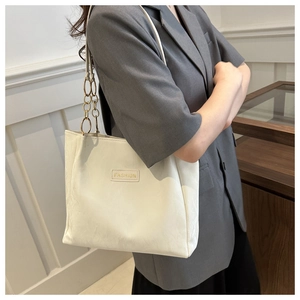 Primo piano di una borsa tote bianca con etichetta FASHION e catena dorata su modella