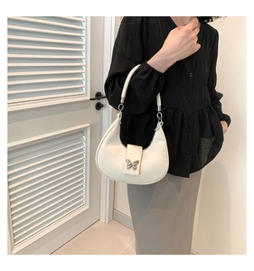 Dettaglio della borsa a mezzaluna in pelle PU bianca con fibbia decorativa a farfalla